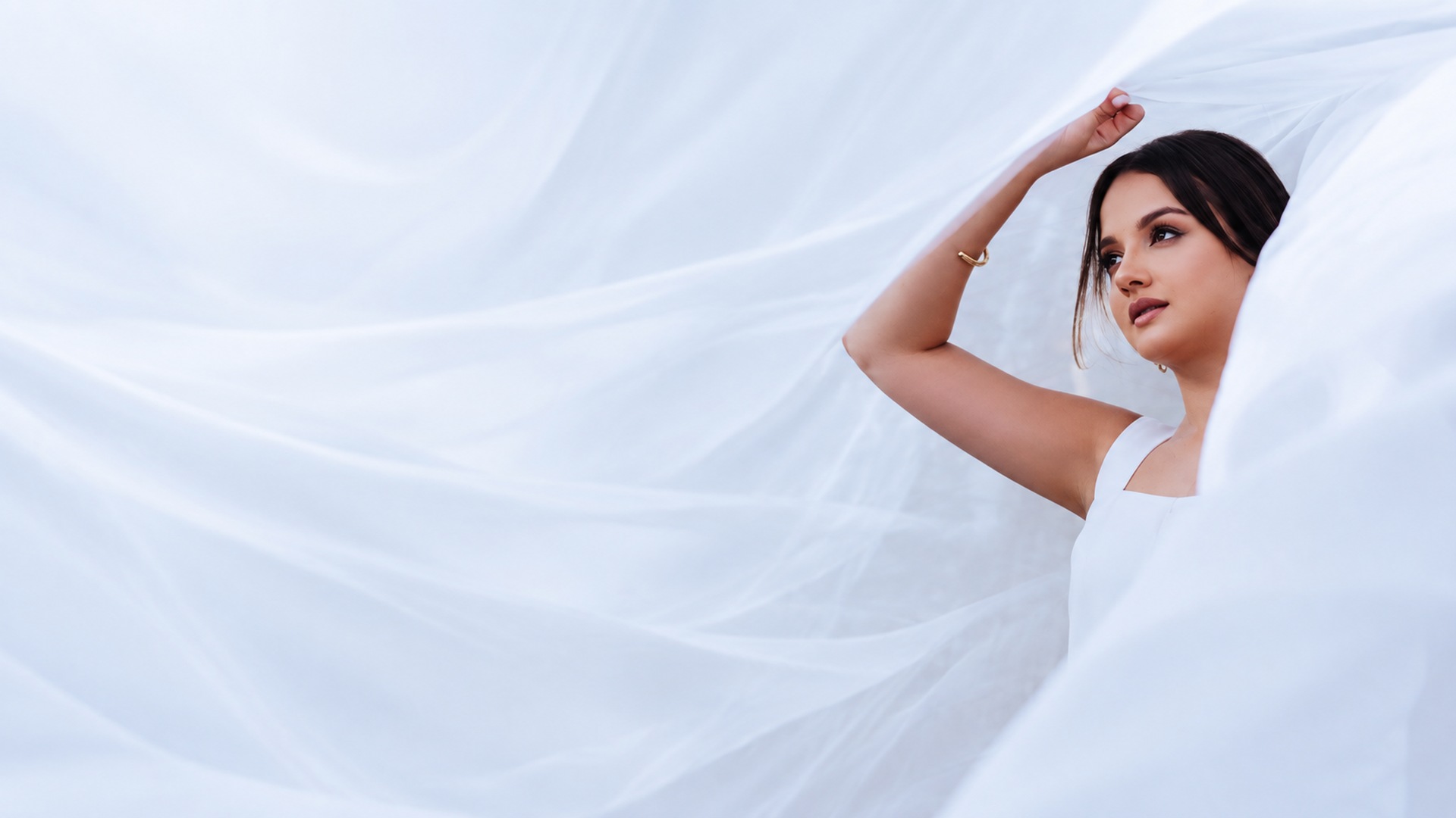 Noiva sob tecido branco fluido, em uma produção elegante